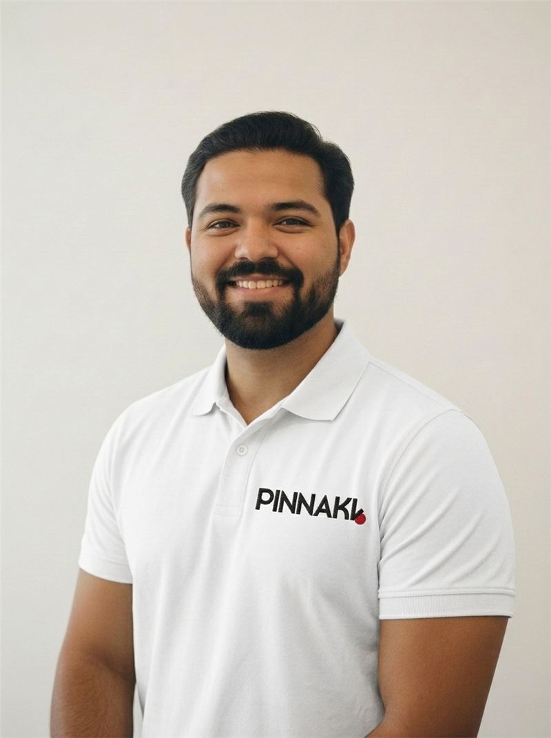 Muhammad Shariq, founder of Pinnakl, smiling in a white Pinnakl polo